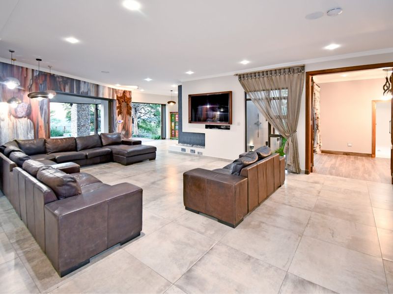 Spacious open-plan living area featuring large format floor tiles, recessed lighting, and a modern built-in fireplace with seamless access to the outdoor area.