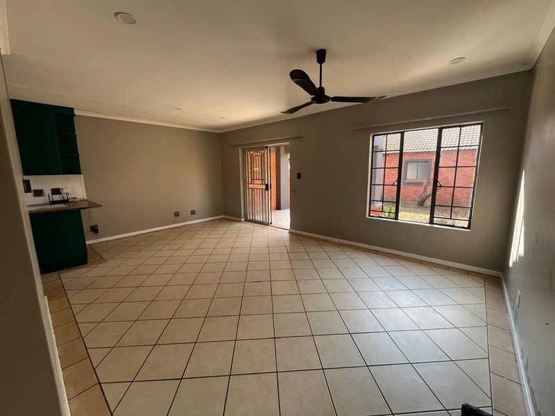 Spacious open-plan living area featuring tiled flooring, a ceiling fan, recessed lighting, and direct access to an outdoor patio through a sliding security door.