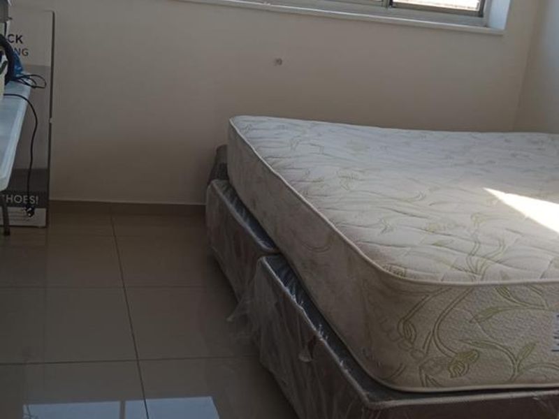 A bedroom featuring large aluminium-framed windows providing natural light and neutral tiled flooring throughout.