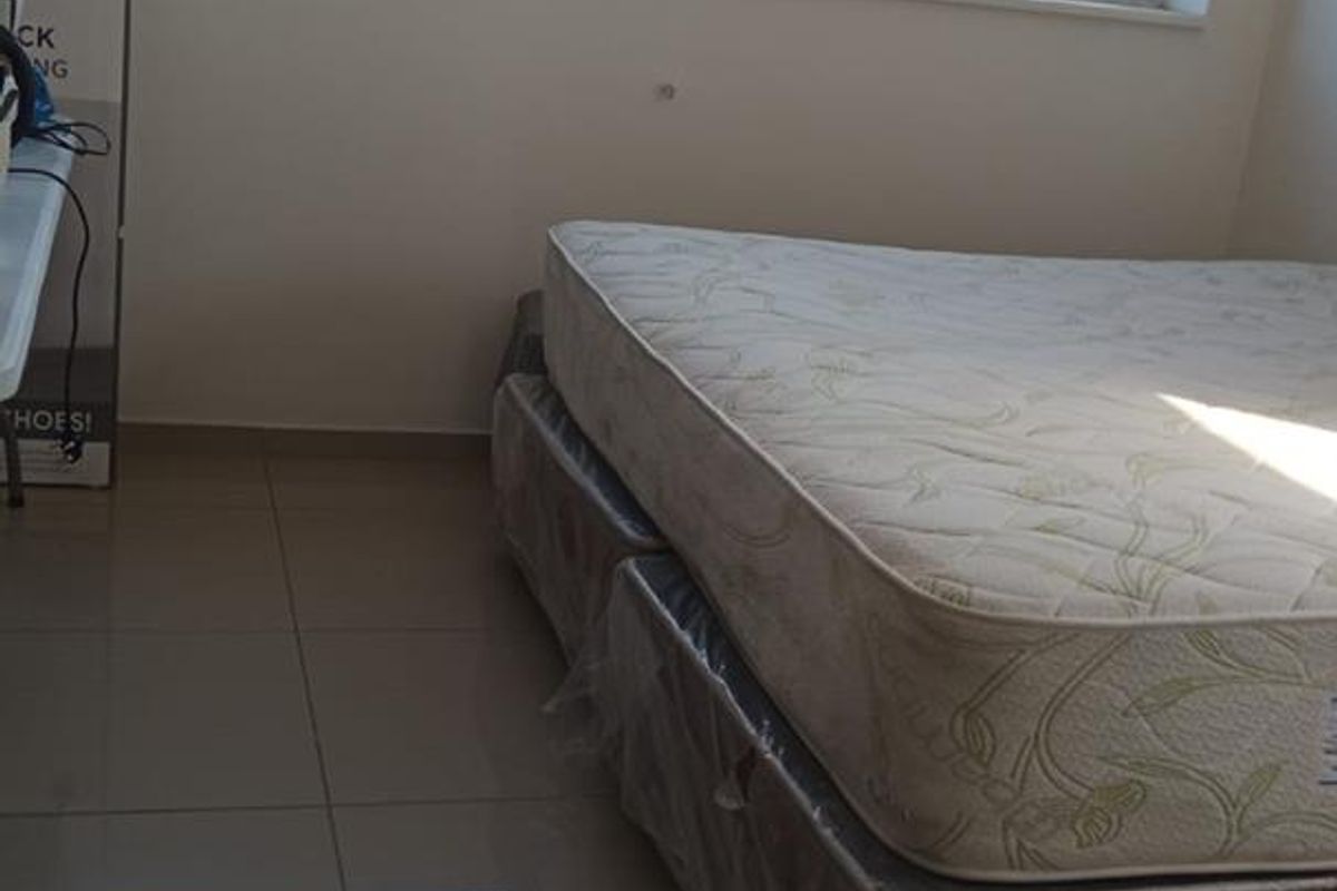 A bedroom featuring large aluminium-framed windows providing natural light and neutral tiled flooring throughout.
