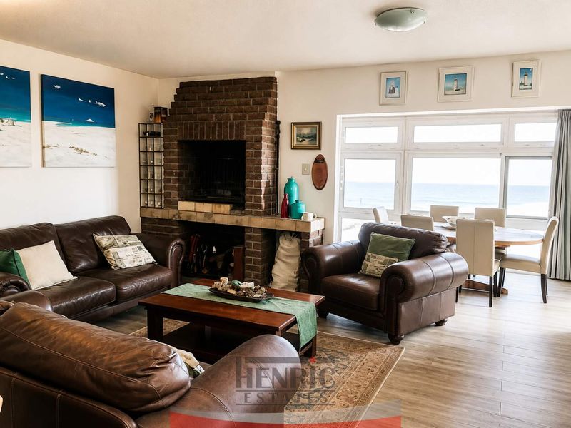 Open plan living and dining area featuring a prominent brick fireplace and large windows with ocean views.
