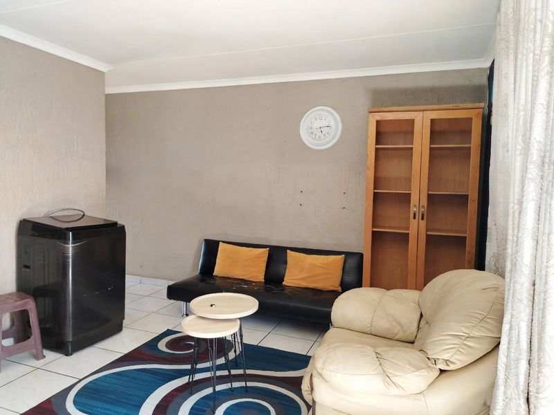 A living room area featuring tiled flooring and coved ceilings, currently requiring minor wall repairs and cosmetic updates.