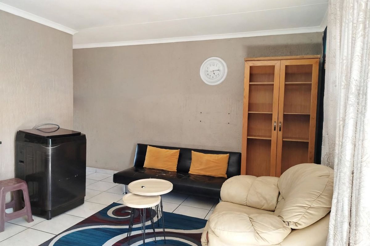 A living room area featuring tiled flooring and coved ceilings, currently requiring minor wall repairs and cosmetic updates.