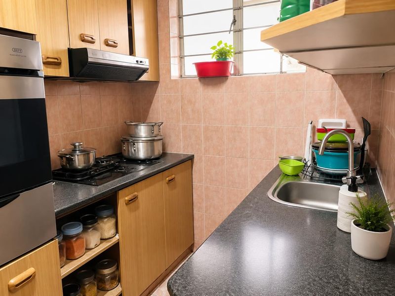 A compact kitchen featuring laminate cabinetry, granite countertops, a built-in oven, gas hob, and a tiled backsplash with a window for natural light.