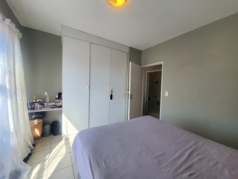 A bedroom featuring built-in cupboards, tiled flooring, and direct access to an adjoining bathroom.
