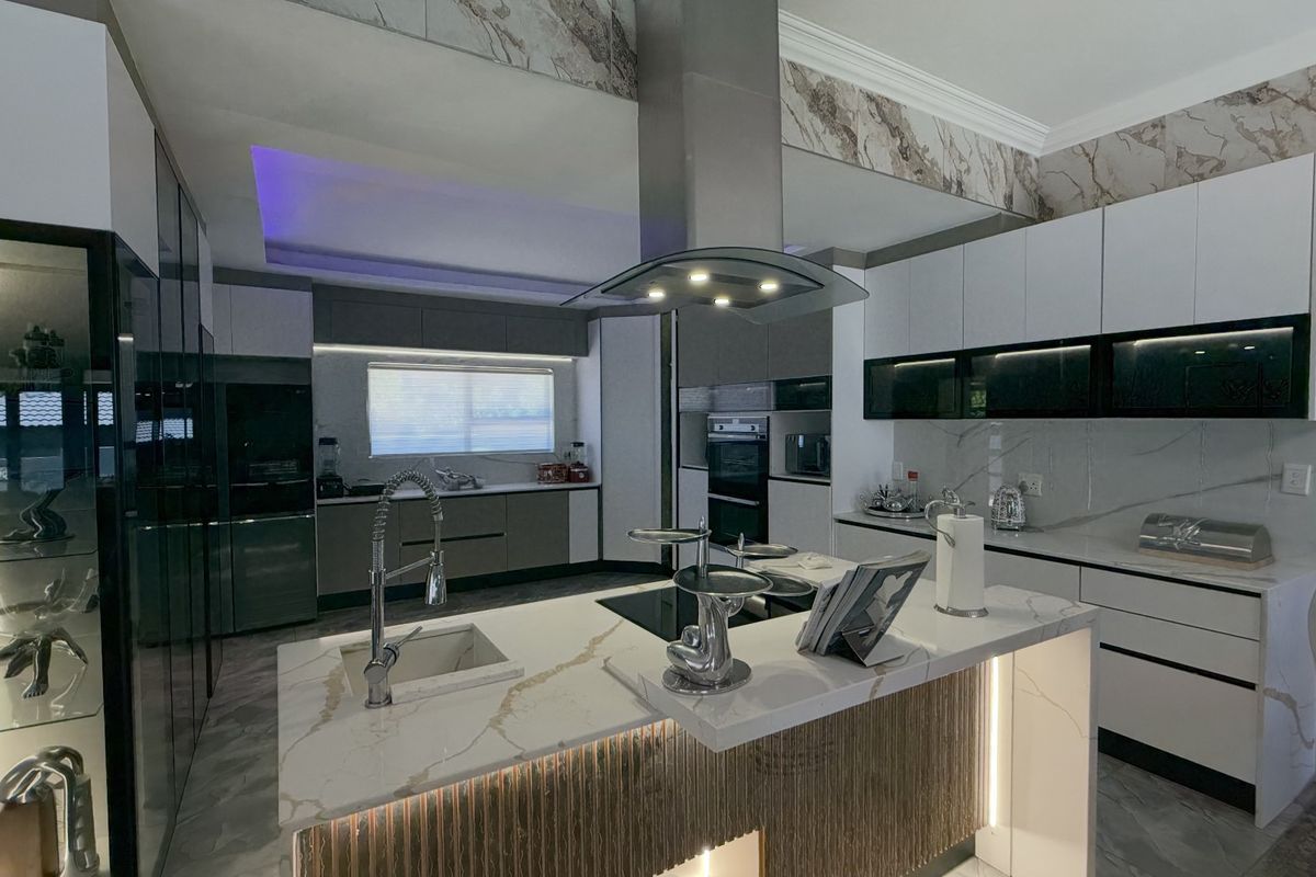 Modern, high-end kitchen featuring a central island with stone countertops, integrated appliances, sleek cabinetry, and sophisticated LED accent lighting.