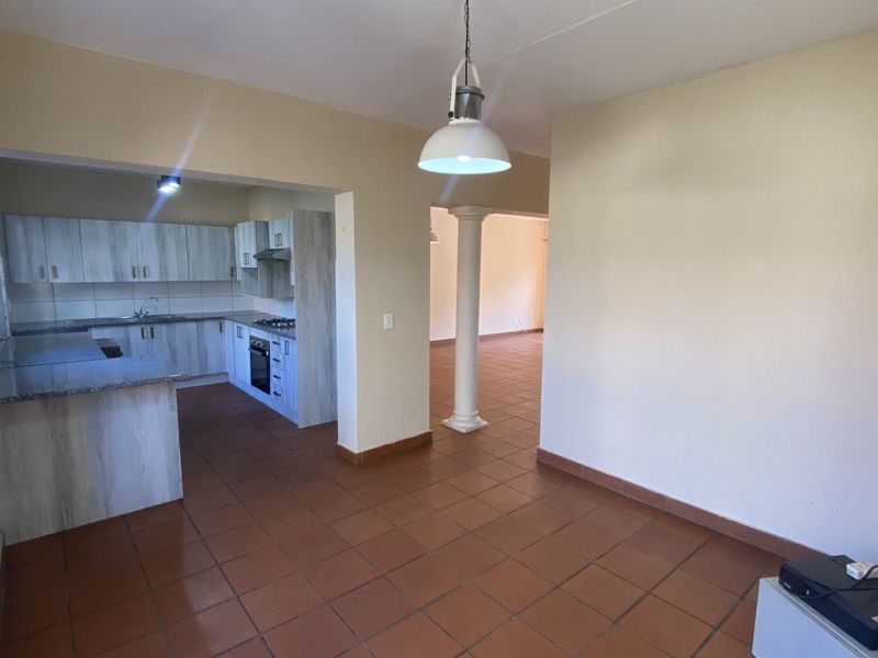 Spacious open-plan living area featuring a functional kitchen with built-in cabinetry, granite countertops, and tiled flooring throughout.