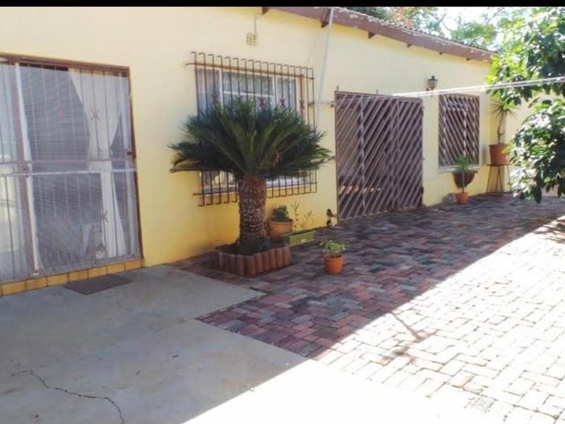 Rear exterior view of the property featuring a paved patio area, security bars on windows, and sliding door access.