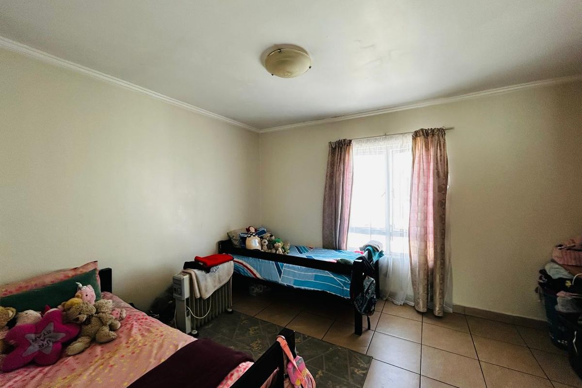 A functional bedroom featuring tiled flooring, a central ceiling light, and a window providing natural light.