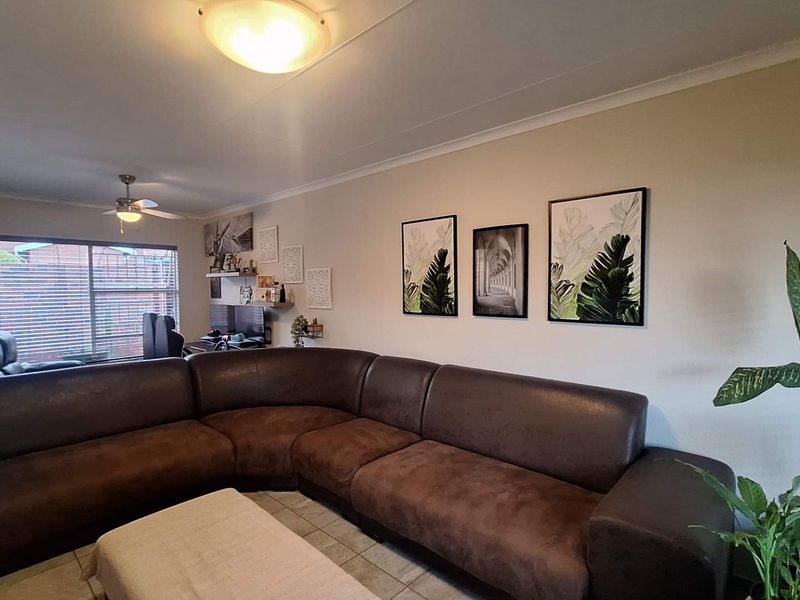 A comfortable living room featuring tiled flooring, a ceiling fan, and neutral wall finishes, providing a functional and inviting space for relaxation.