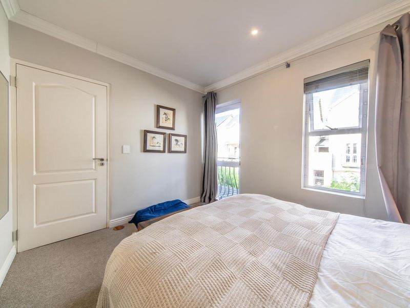 A well-maintained bedroom featuring neutral walls, carpeted flooring, built-in cupboards, and direct access to a small balcony.