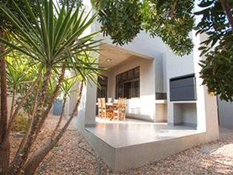 A covered patio area featuring a built-in braai and tiled flooring, providing a functional outdoor entertainment space.