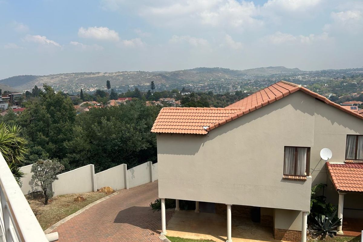 Elevated view of the townhouse rear exterior featuring a paved driveway, terracotta tiled roof, and scenic hillside landscape.