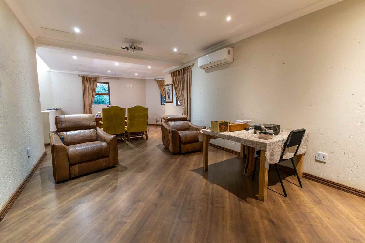 Spacious living area featuring laminate flooring, recessed downlighting, and a wall-mounted air conditioning unit, offering a versatile layout for relaxation and dining.