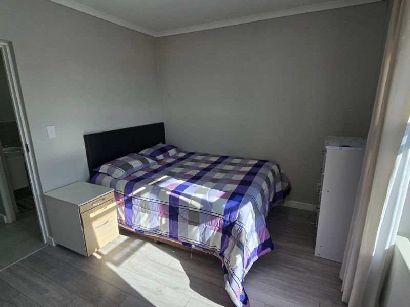A well-lit bedroom featuring modern laminate flooring and neutral wall tones, providing a clean and functional living space.