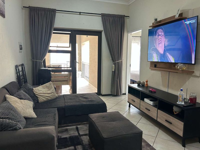 A comfortable living room featuring tiled flooring and a sliding glass door providing access to an outdoor balcony area.