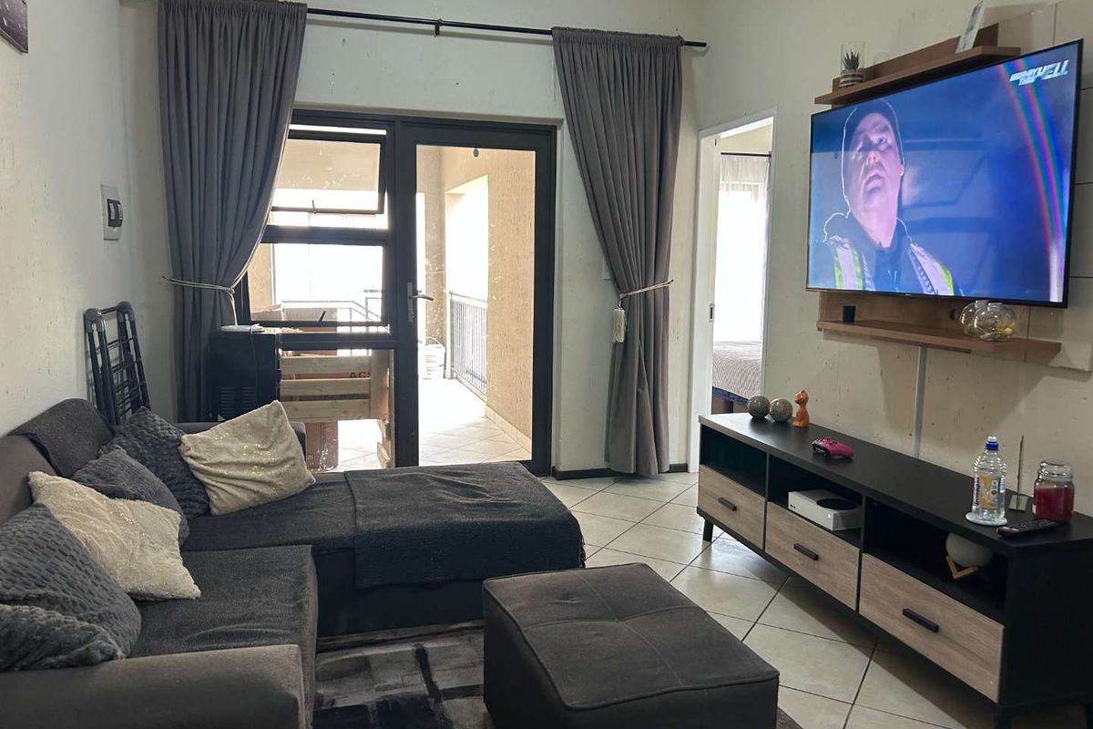 A comfortable living room featuring tiled flooring and a sliding glass door providing access to an outdoor balcony area.
