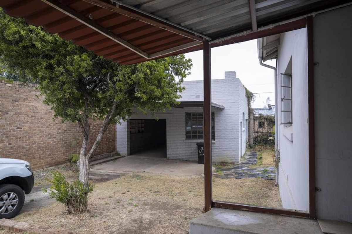 View from a covered patio looking across the rear garden towards a detached brick garage structure.