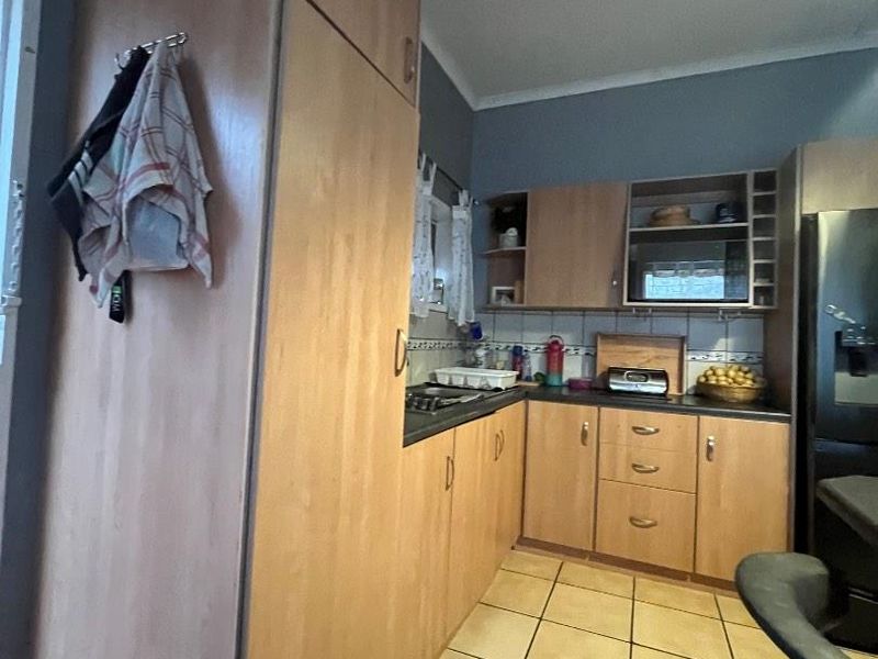 A functional kitchen featuring laminate cabinetry, tiled flooring, and a tiled backsplash, offering a practical layout for daily meal preparation.