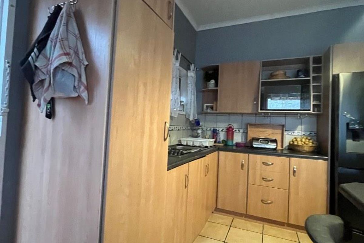 A functional kitchen featuring laminate cabinetry, tiled flooring, and a tiled backsplash, offering a practical layout for daily meal preparation.