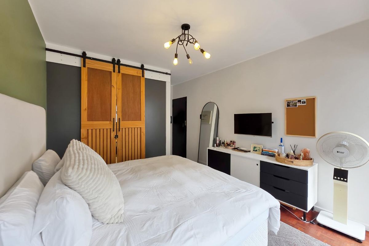 A well-maintained bedroom featuring hardwood flooring, a distinctive sliding barn door, and a modern overhead light fixture.