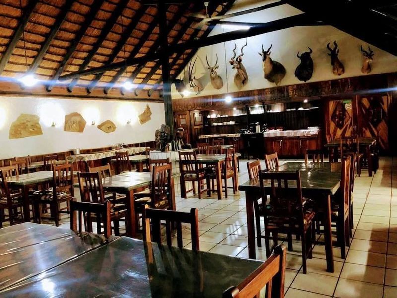 Spacious dining area featuring a high thatched roof with exposed timber trusses and tiled flooring, suitable for lodge-style hospitality.