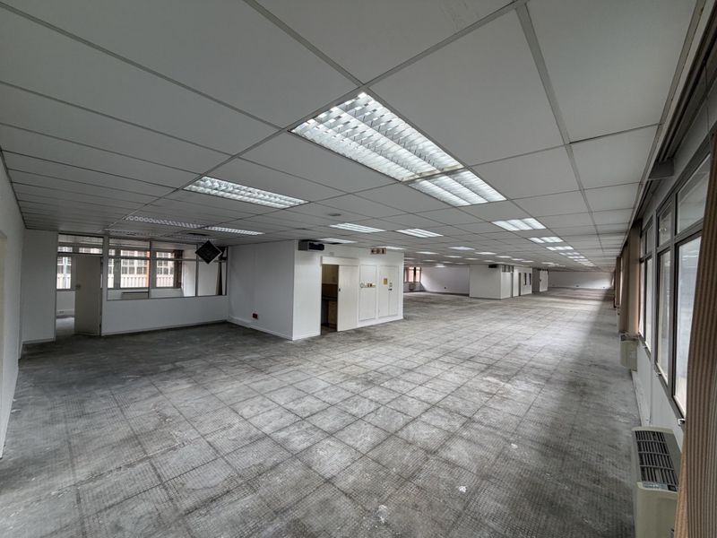 Expansive open-plan industrial office space featuring suspended ceilings, recessed lighting, and large windows, currently vacant and ready for refurbishment.