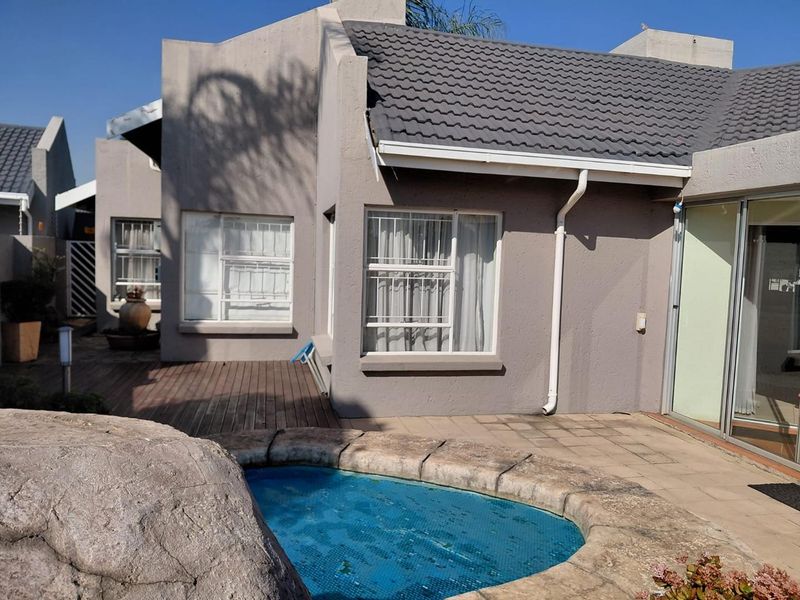 Rear exterior view of the townhouse featuring a plunge pool, timber decking, paved patio area, and sliding glass doors leading to the interior.