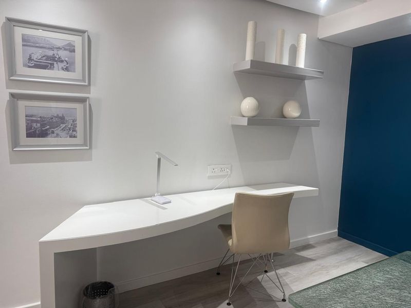 A modern home office space featuring a sleek built-in desk, floating wall shelves, and contemporary finishes.