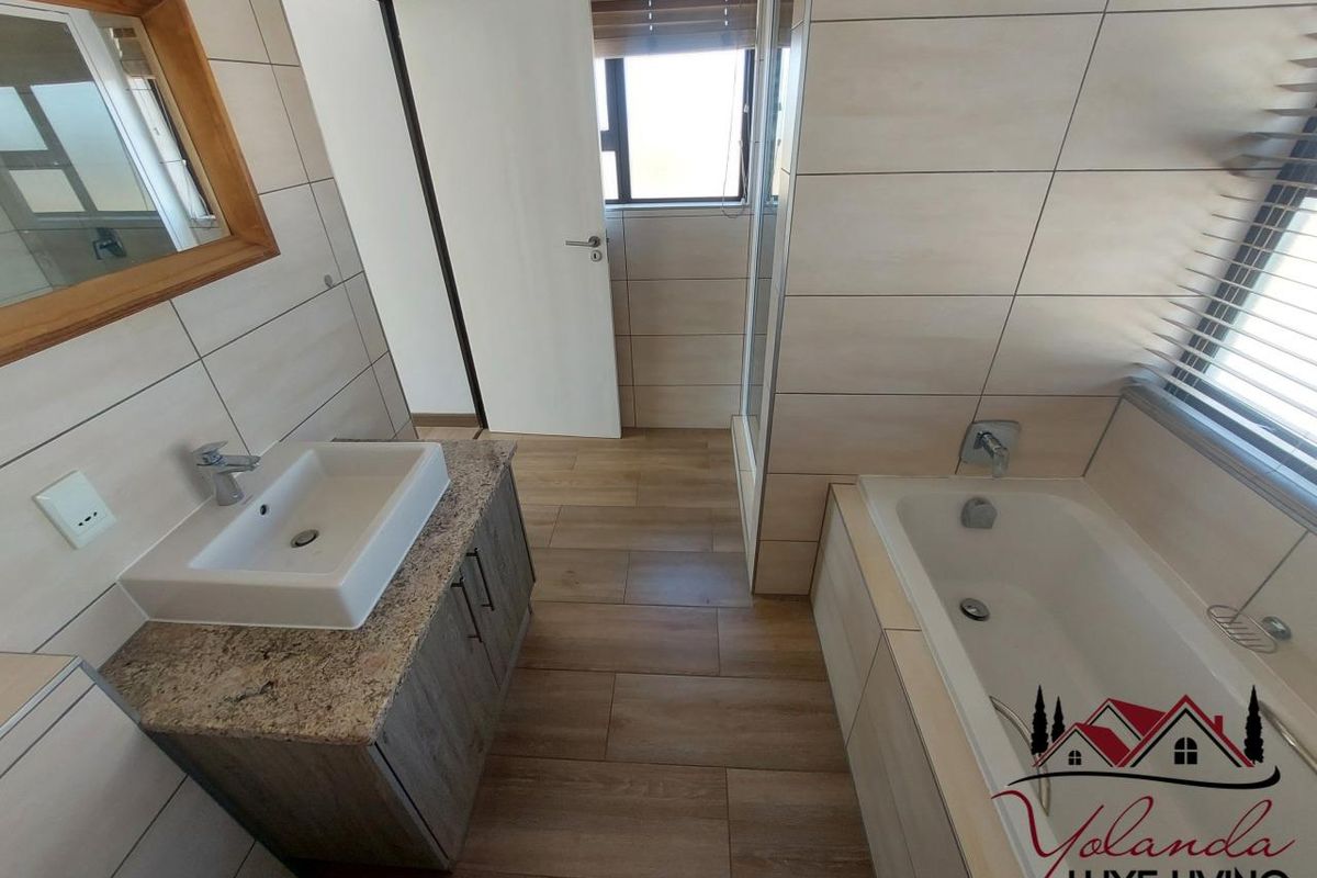 A modern bathroom featuring a vessel sink on a granite vanity, a built-in bathtub, and a separate shower enclosure with neutral wall and floor tiling.