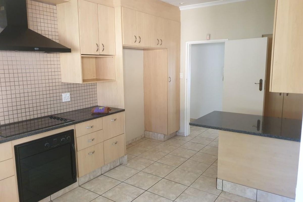A functional kitchen featuring light wood cabinetry, granite countertops, built-in oven and hob, and tiled flooring, offering a clean and practical workspace.