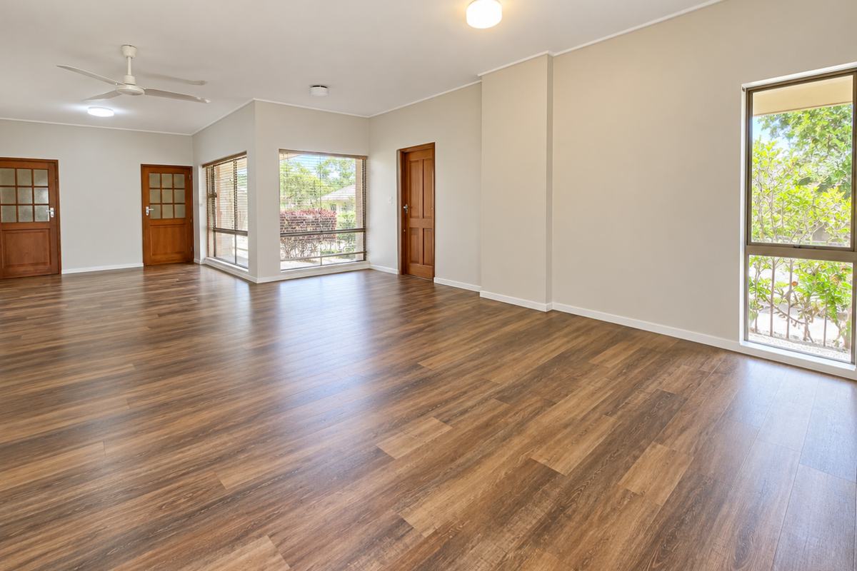 Spacious, light-filled living area featuring modern laminate wood flooring, neutral walls, and large windows providing ample natural light and garden views.