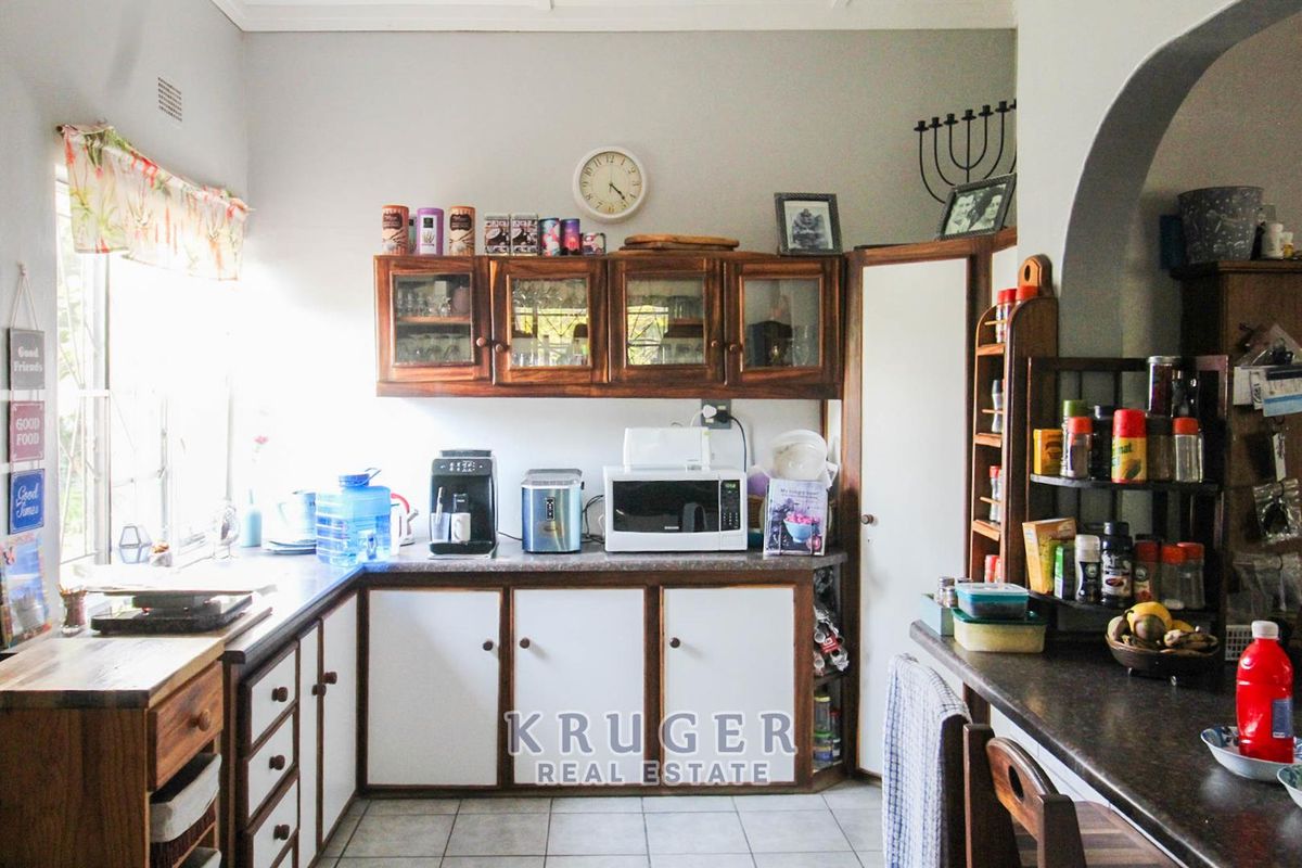 A functional kitchen featuring wooden cabinetry, laminate countertops, and tiled flooring, with an open archway leading to adjacent living spaces.