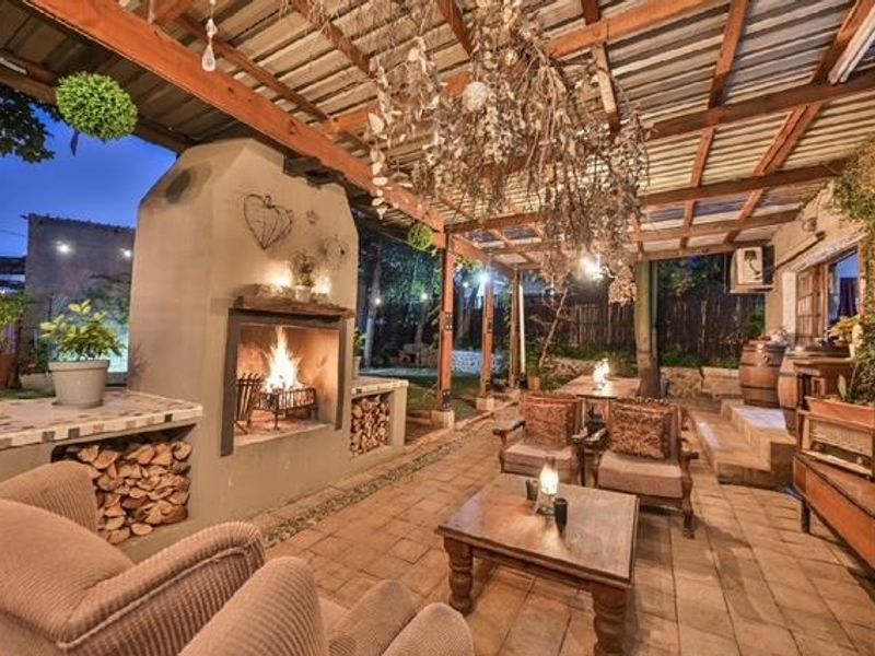 A spacious covered outdoor patio featuring a large built-in fireplace, timber pergola structure, and paved flooring, ideal for year-round entertaining.