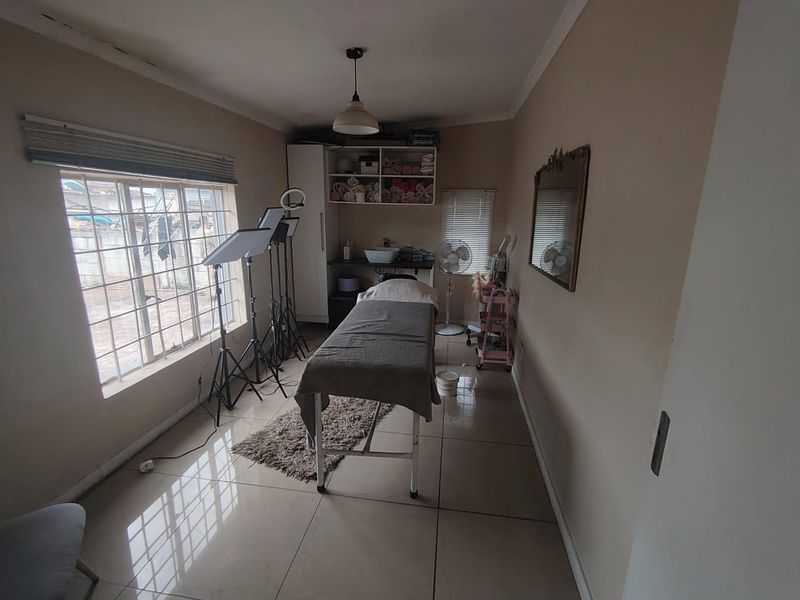 A functional office space featuring tiled flooring, built-in shelving, and a small integrated basin, currently utilized as a treatment room.