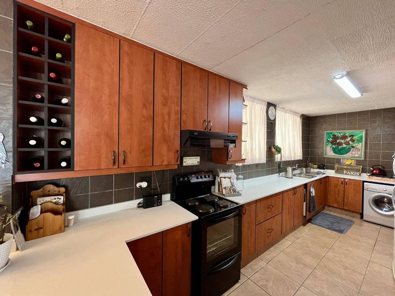 Functional kitchen featuring wood-tone cabinetry, integrated wine rack, dark tiled backsplash, and built-in oven with extractor fan.