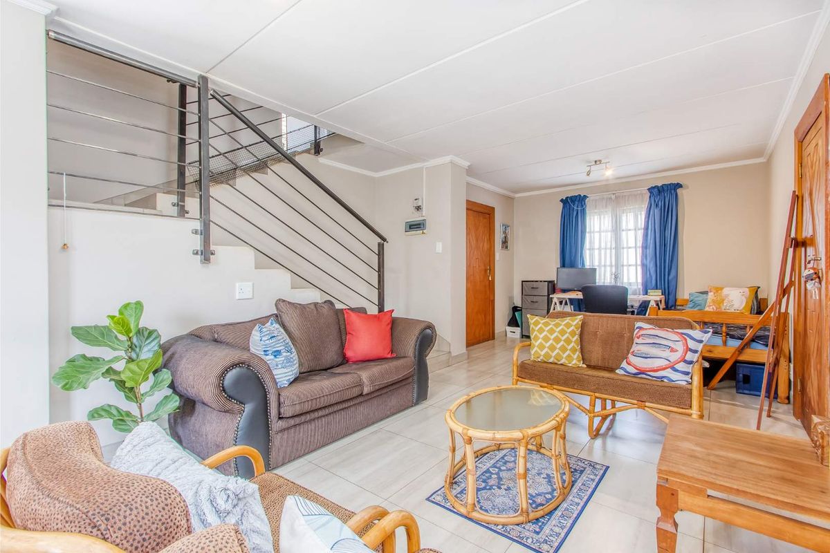 A spacious living area featuring tiled flooring and an open-plan staircase with a modern metal balustrade.