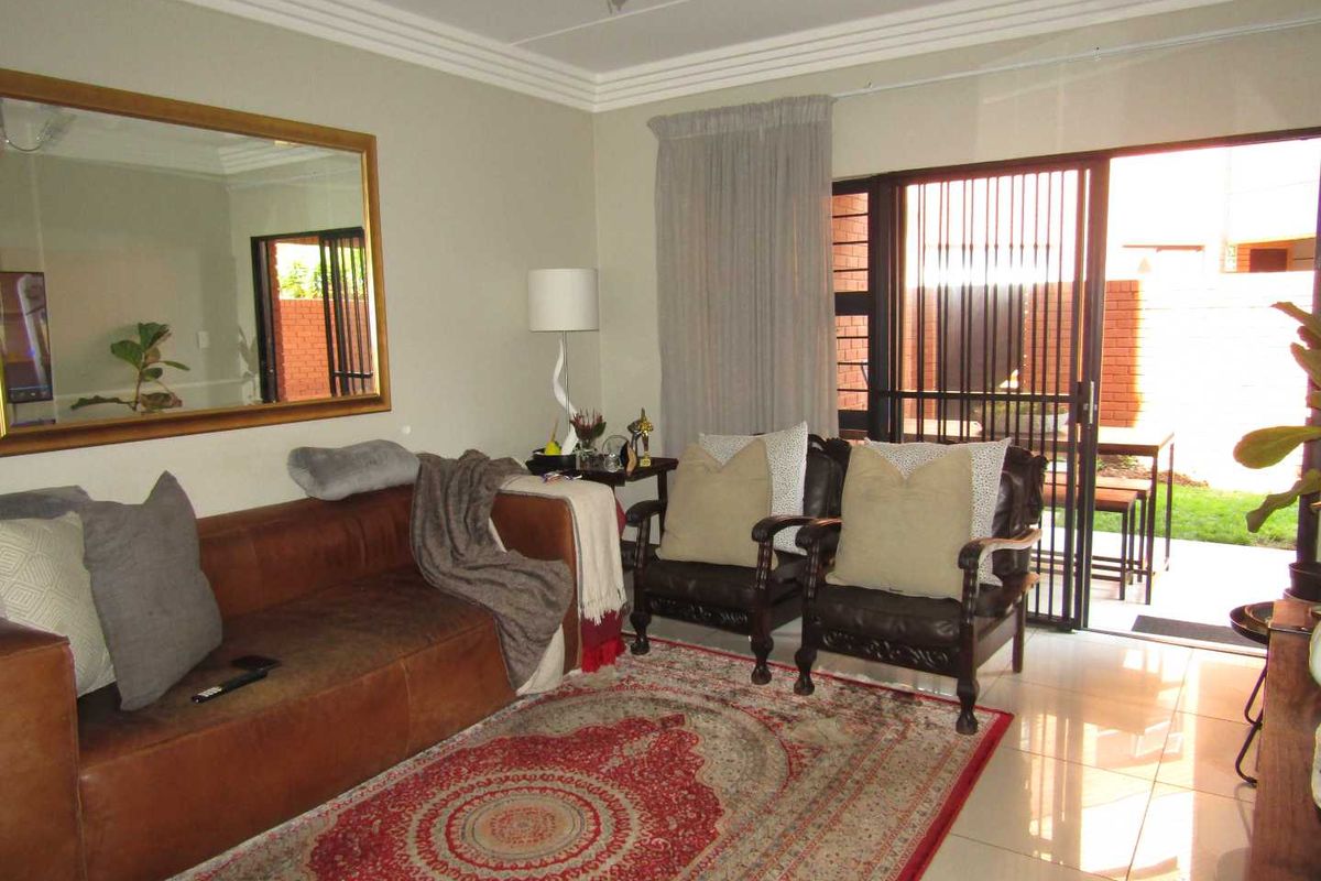 A living room featuring tiled flooring, crown molding, and a sliding glass door providing access to an outdoor patio area.