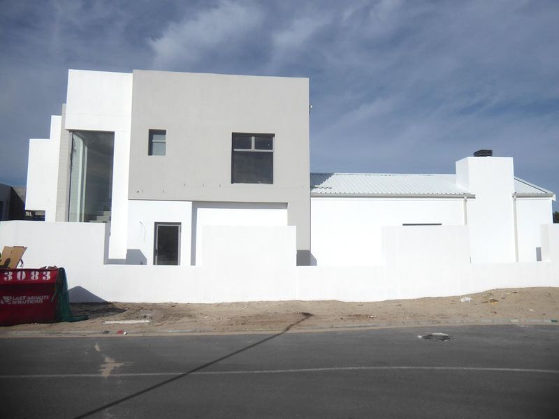 Modern two-story residential property under construction featuring a clean white and grey plastered facade, metal roofing, and a perimeter boundary wall.