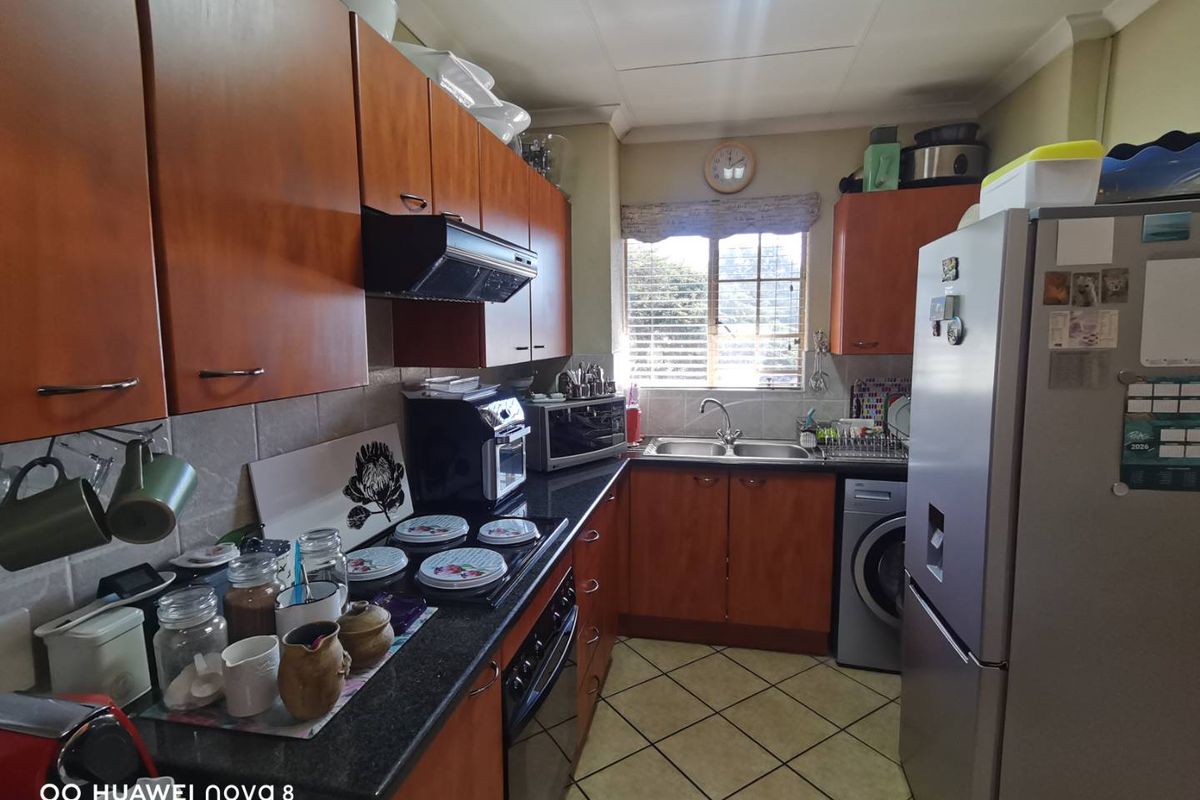 A functional kitchen featuring wood-veneer cabinetry, dark granite countertops, a double-basin sink, and integrated space for a washing machine.