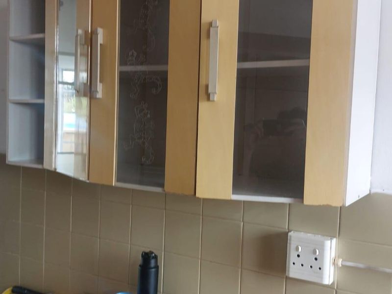 A kitchen area featuring wall-mounted cabinetry, a tiled backsplash, and an exposed electrical distribution board.
