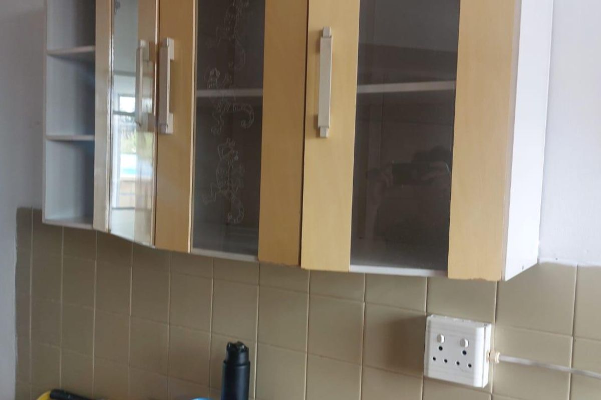 A kitchen area featuring wall-mounted cabinetry, a tiled backsplash, and an exposed electrical distribution board.