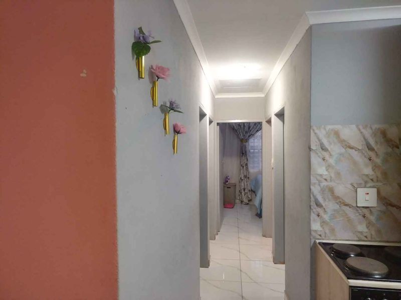 A functional hallway featuring tiled flooring and a partial view of an adjacent kitchen area with a built-in stove.