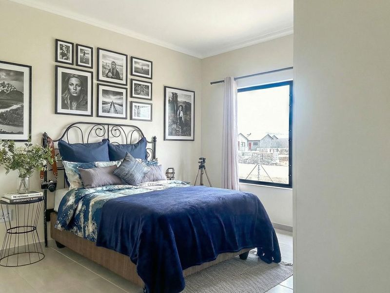 A well-maintained bedroom featuring neutral wall tones, tiled flooring, and a large window providing natural light.