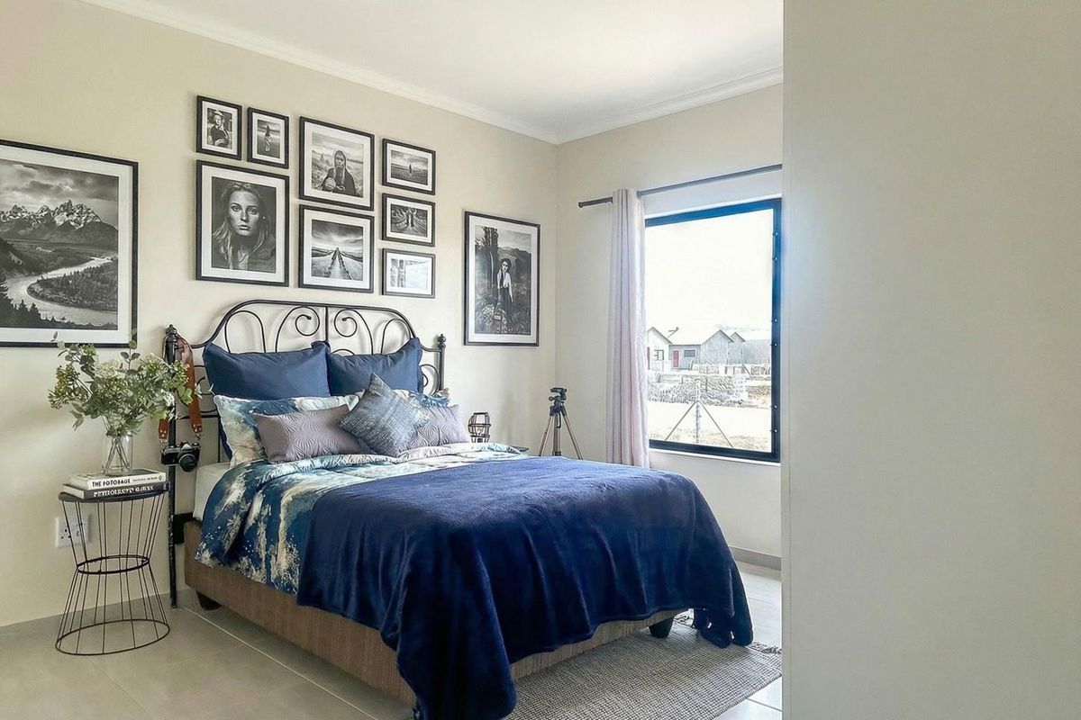 A well-maintained bedroom featuring neutral wall tones, tiled flooring, and a large window providing natural light.