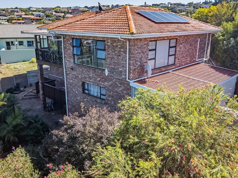 Aerial view of a double-story face brick house featuring a terracotta tiled roof with integrated solar panels and a balcony.