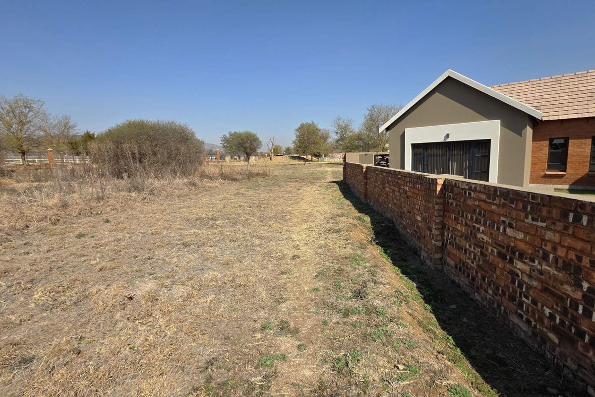 A view of the rear yard area featuring a brick boundary wall and a portion of the residential building structure.