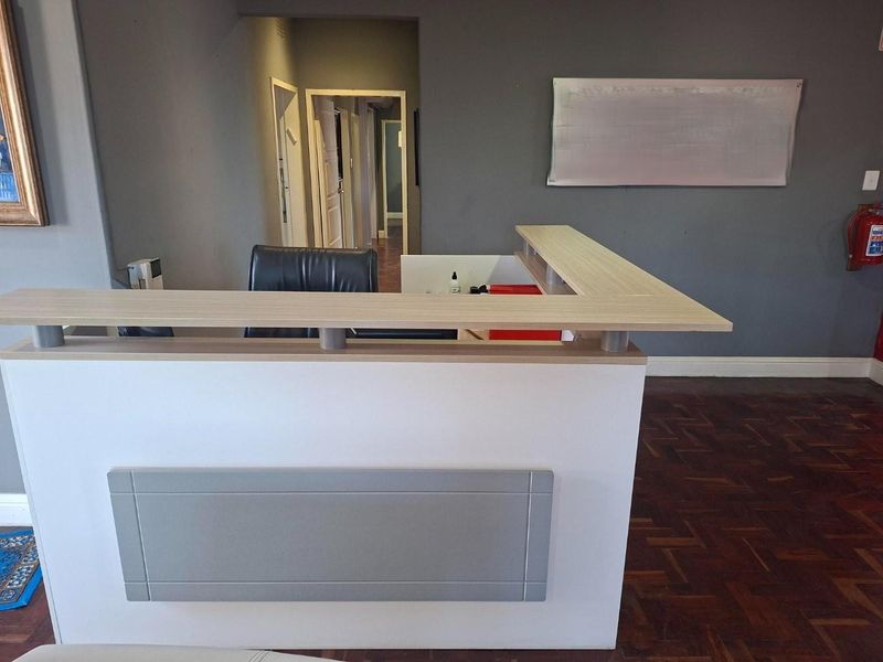 An entry area featuring a built-in reception desk and traditional parquet flooring, leading into a hallway with multiple doorways.