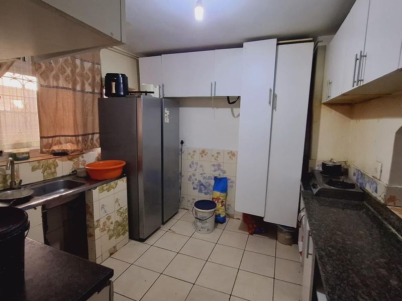 A functional kitchen featuring granite countertops, built-in cabinetry, and tiled flooring. The space requires cosmetic updates to modernize the finishes and improve overall presentation.