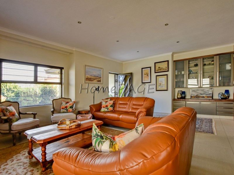 A well-maintained living room featuring tiled flooring, recessed downlighting, and custom built-in display cabinetry.